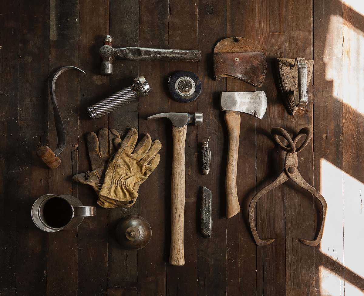 gloves clothes iron, hammer, axe, flashlight and pitcher on brown wooden table tool