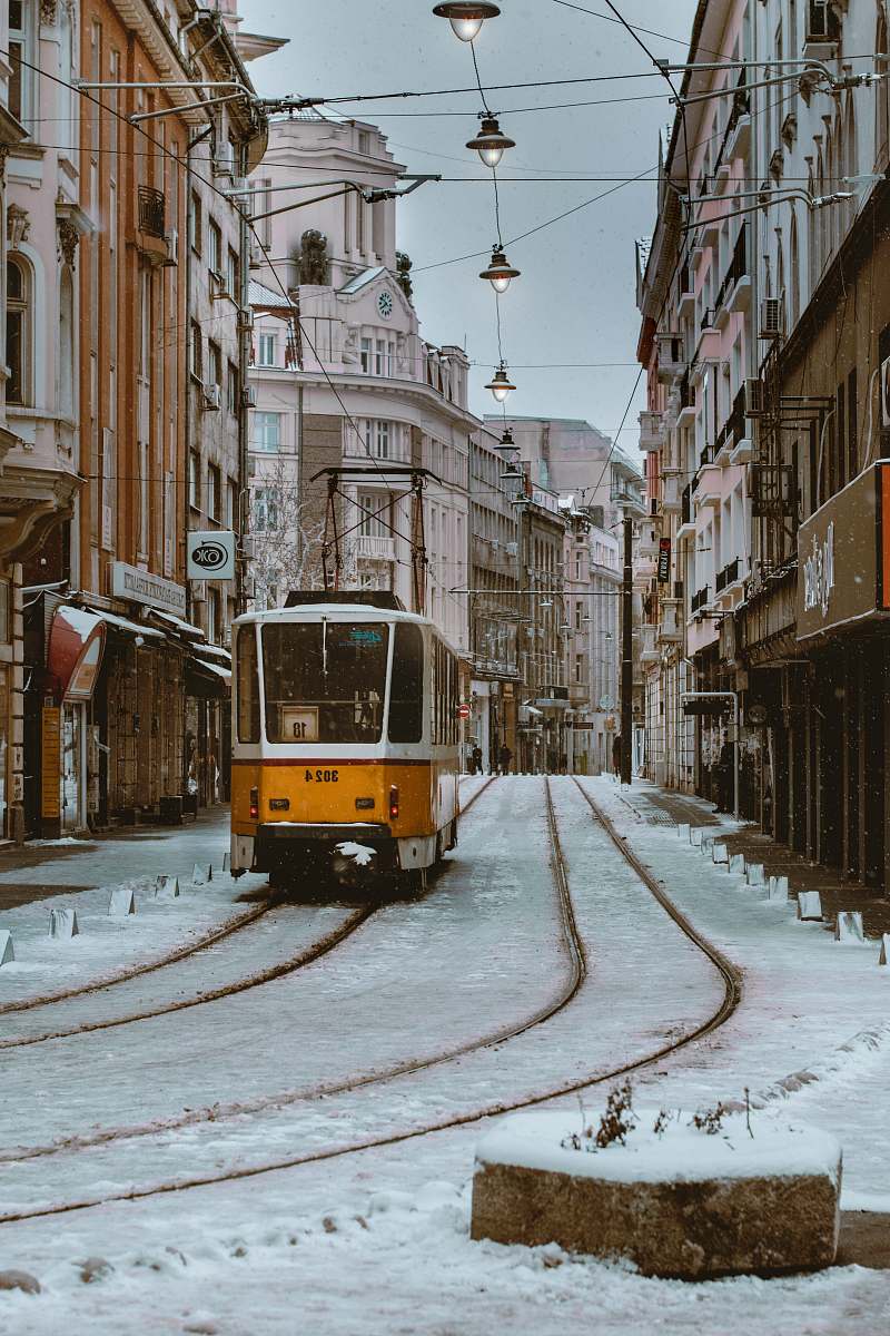 vehicle orange and gray train beside brown concrete building \ cable car