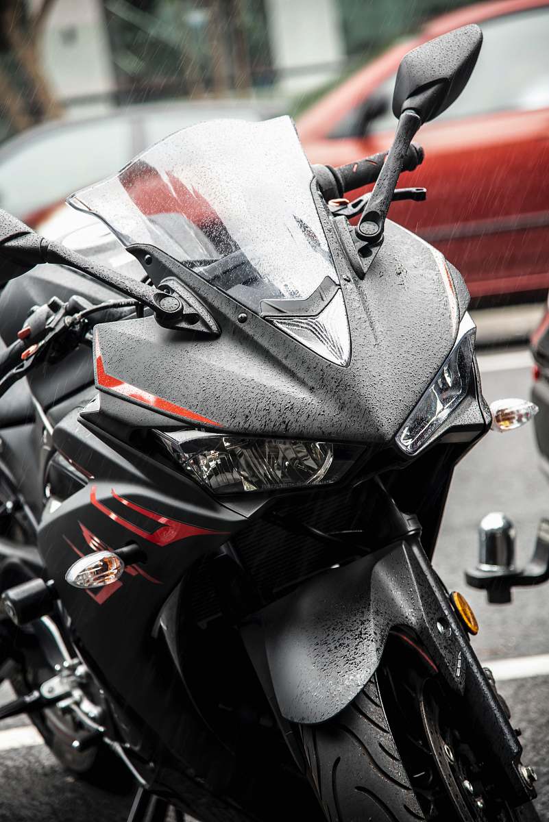 motorcycle black and red Yamaha R1 sports bike near parked car vehicle