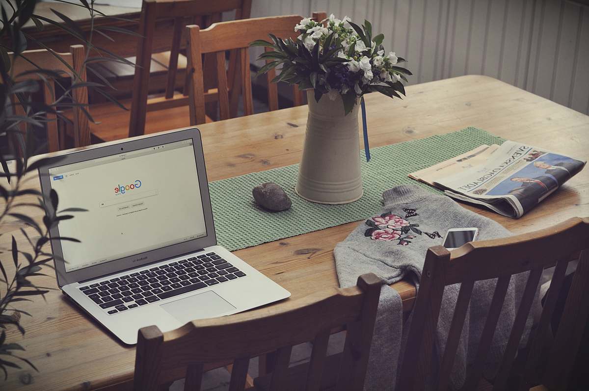 computer laptop on top of table beside vase of flowers laptop