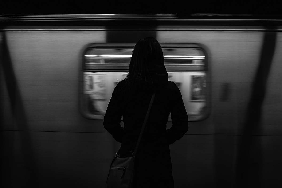 black-and-white grayscale photography of woman standing near running train train
