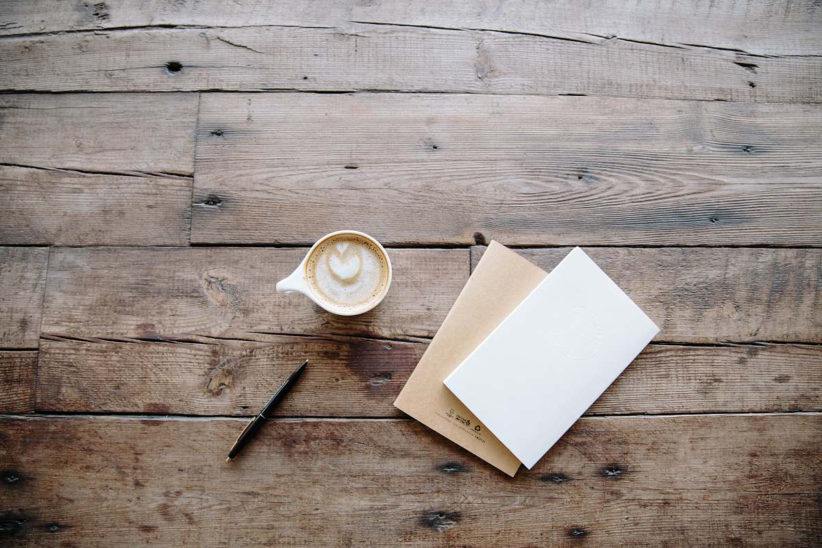 coffee black twist pen near white teacup desk