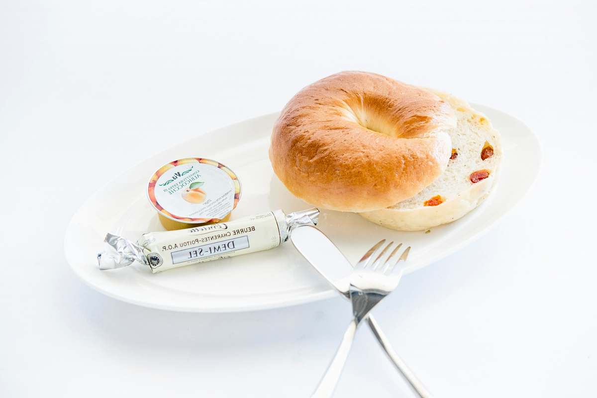 food bread on white plate with fork and table knife bagel
