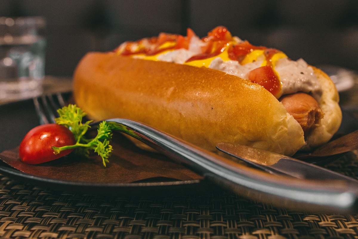 food burger on black plate beside gray stainless steel dining fork hot dog