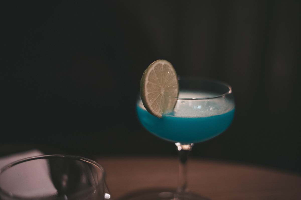 fruit blue liquid long-footed glass with lime citrus fruit