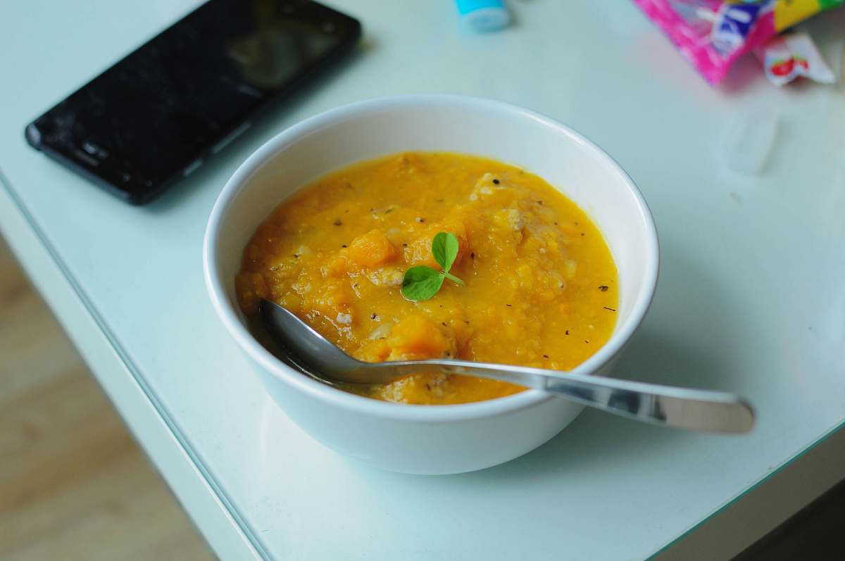 bowl bowl of soup with spoon beside smartphone dish