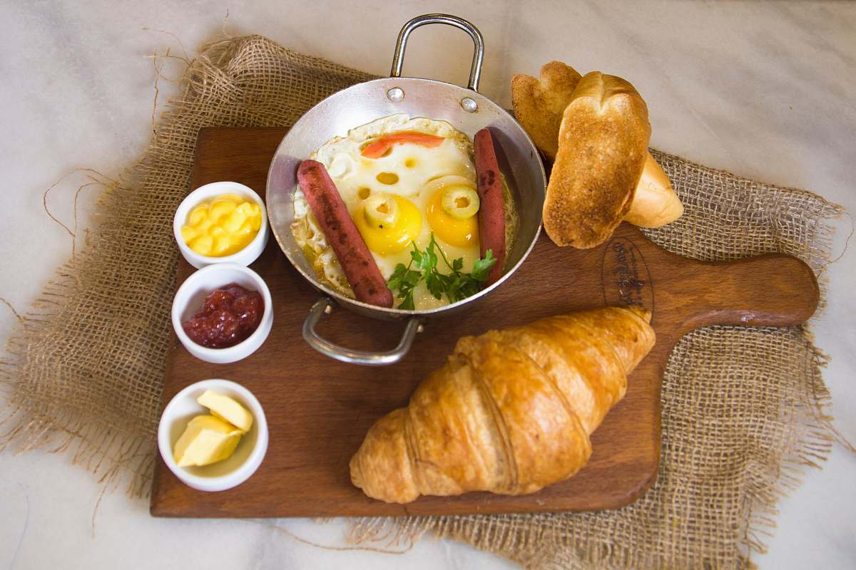 bread bread beside bowl with eggs and hotdog croissant