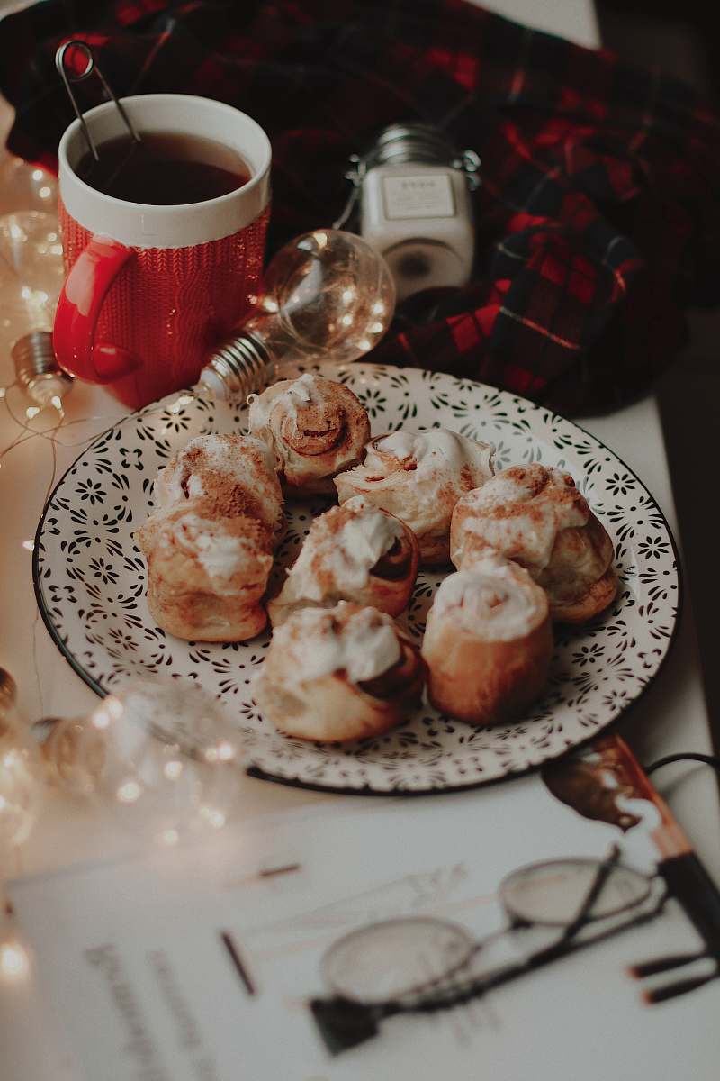 meal bread with cream toppings on round plate near lighted bulb and white and red ceramic mug dish