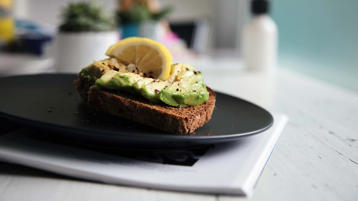 plate brown bread with sliced avocado and lemon on top toast