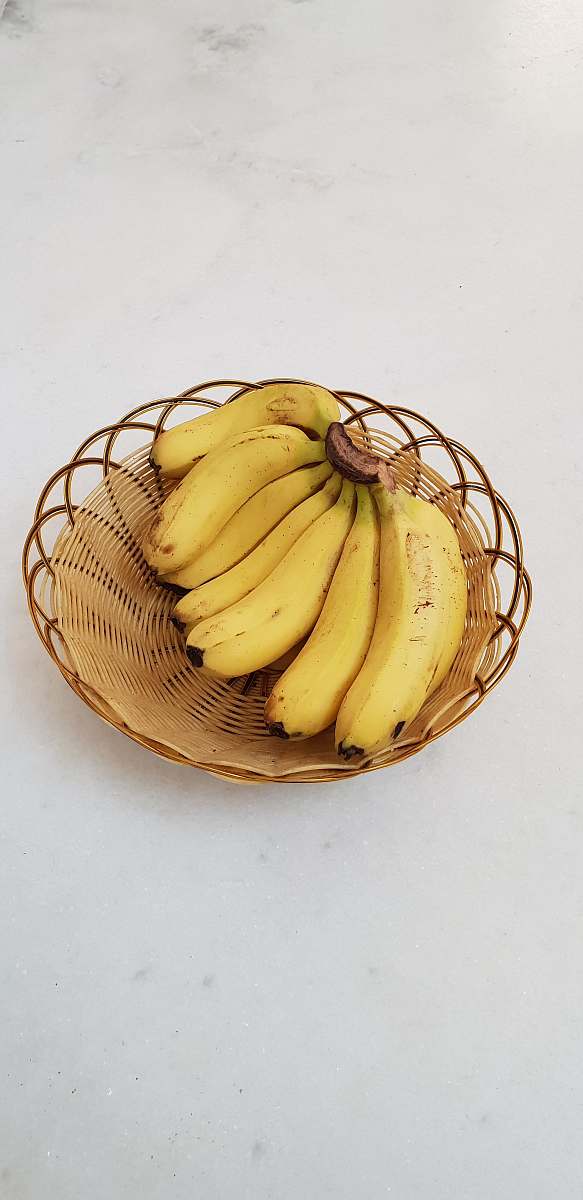fruit bunch of yellow bananas in a brown wicker bowl banana