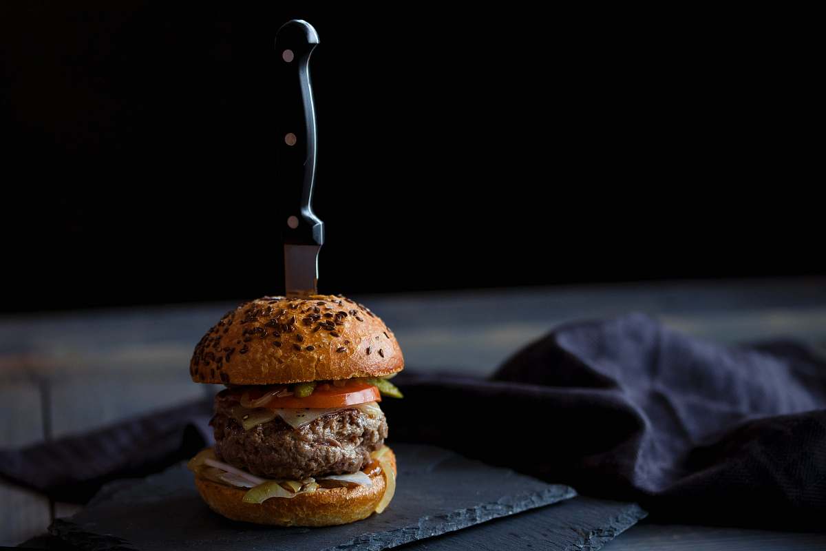 burger burger skewered with knife near black textile bun