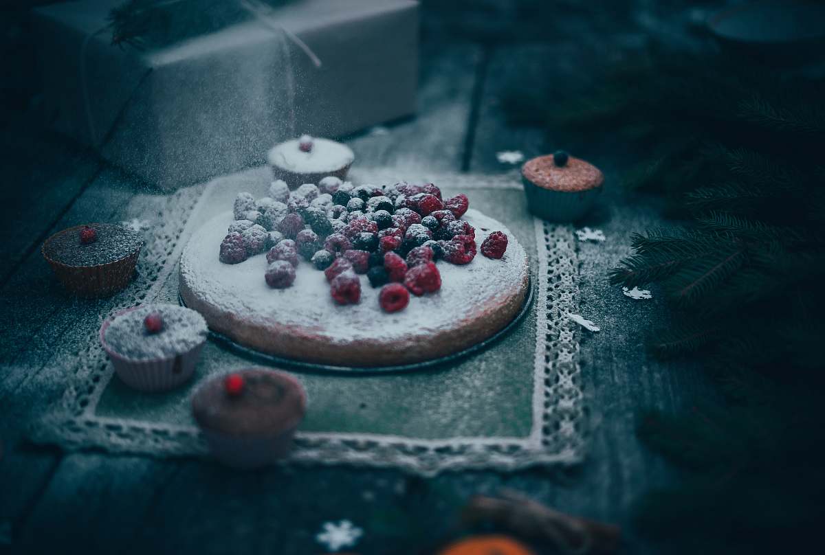 confectionery cake with berries on top near cupcakes sweets