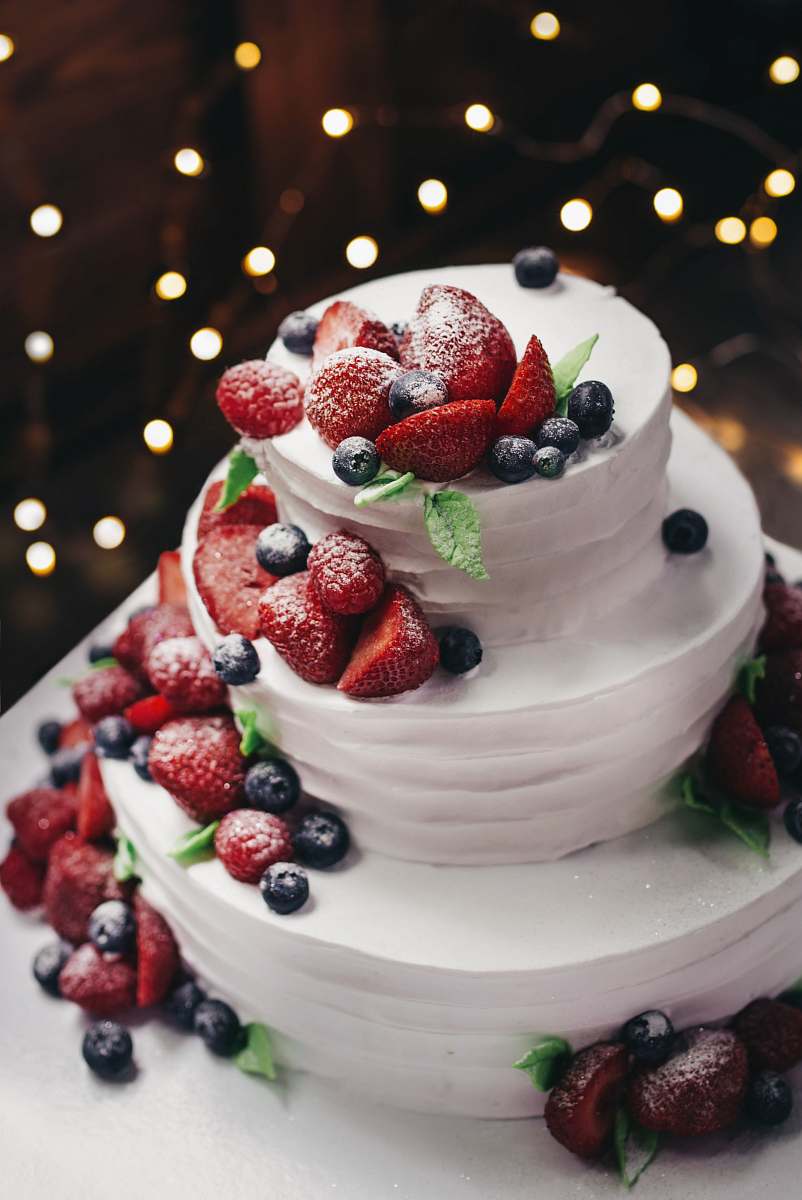 fruit close-up photography of 3-tier vanilla cake with blueberry and strawberry toppings blueberry