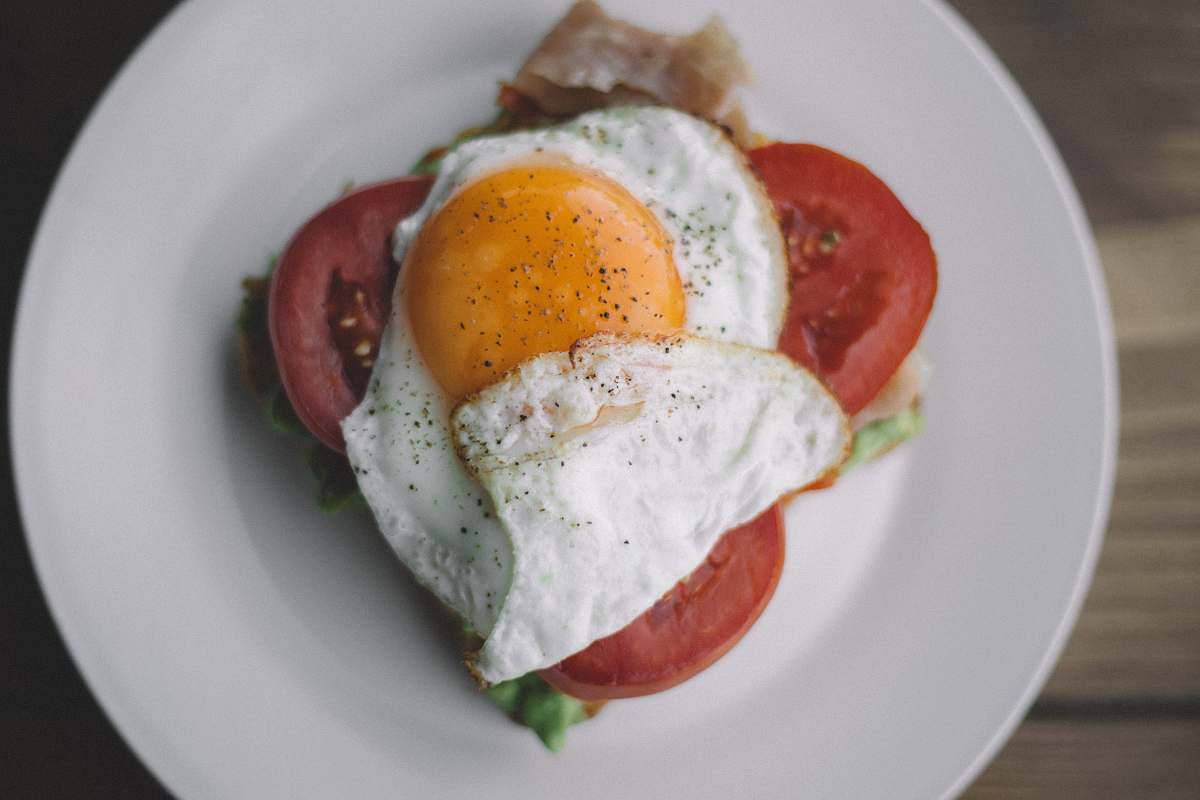 cream fried egg with black pepper and sliced tomatoes egg