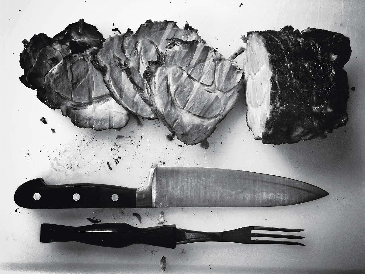 black-and-white grayscale photo of grilled meat beside knife and fork grey