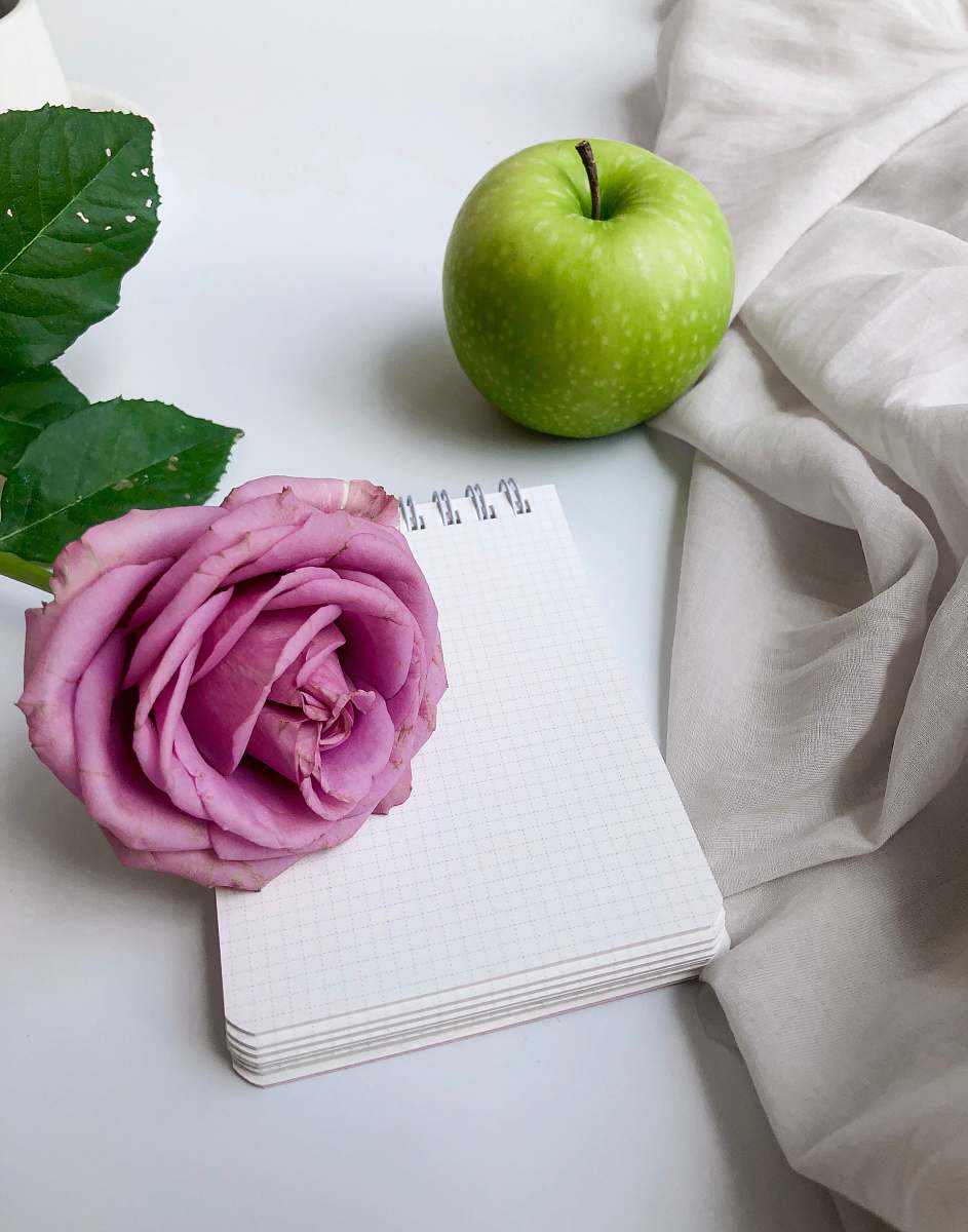 plant green apple near a pink petaled rose flower and white mini-notebook apple
