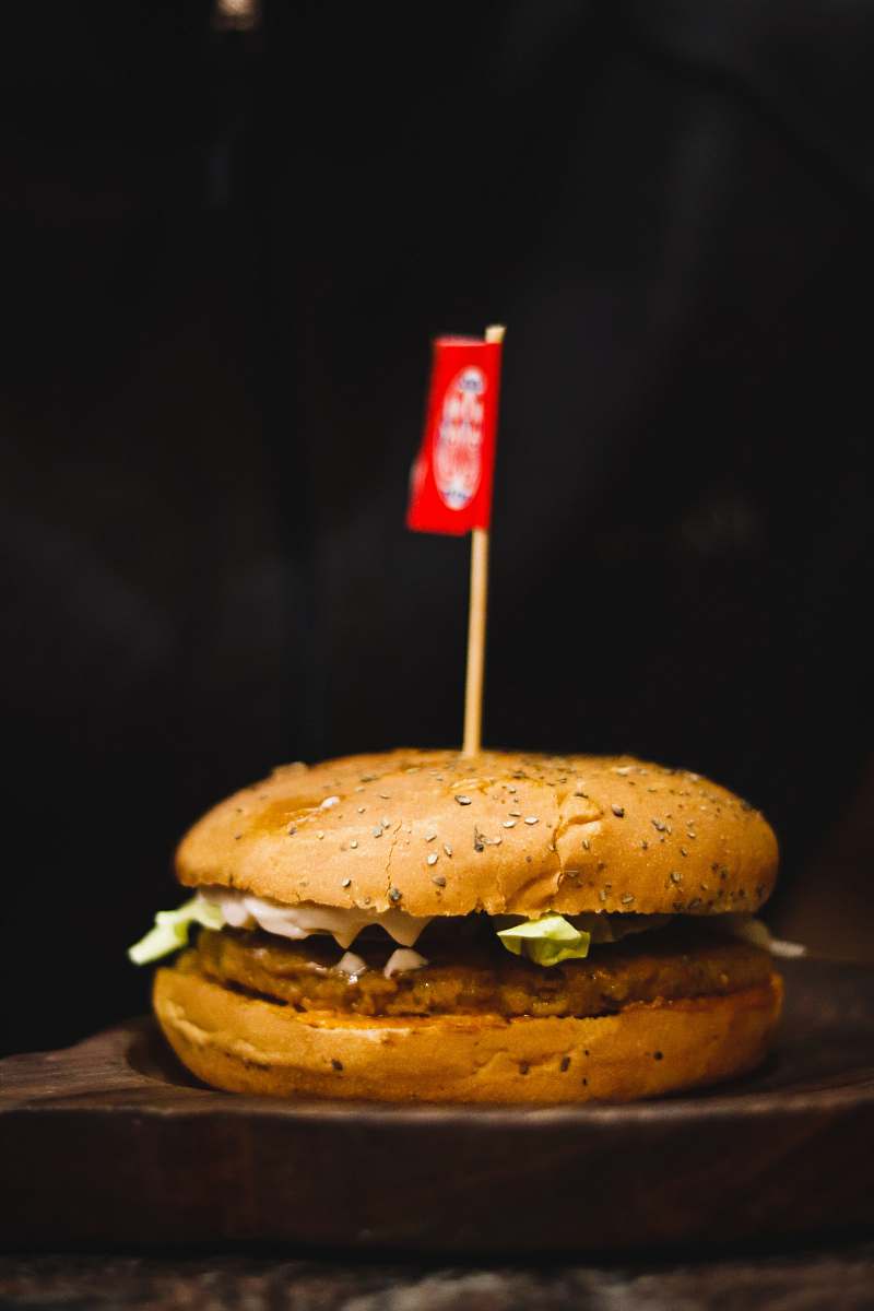 bread hamburger on wooden surface with small flag burger