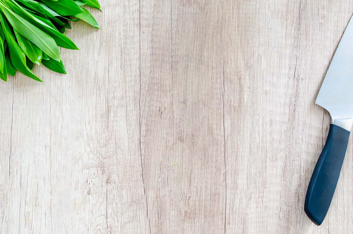 grey kitchen knife and green leaf vegetable on tableto cutting board