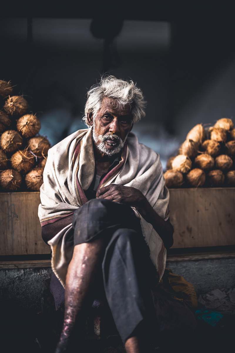 vegetable man sitting beside coconut stand plant