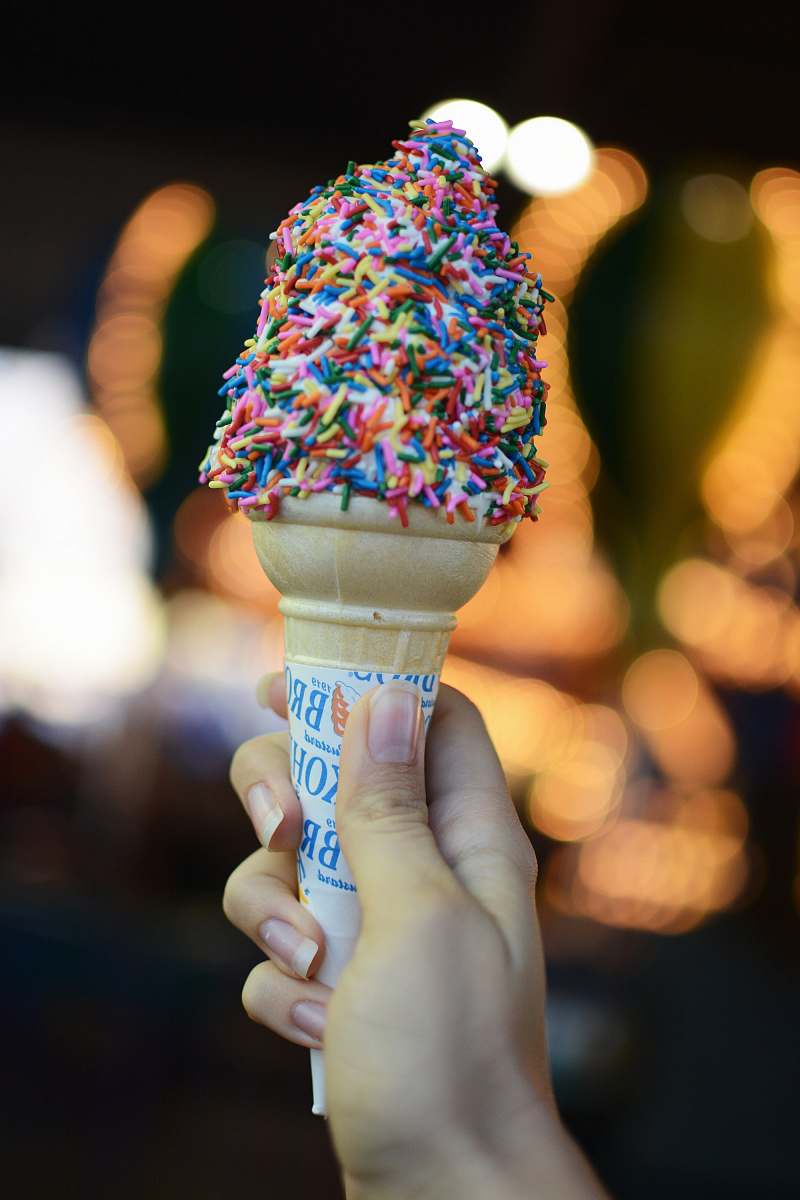 cream person holding cone with sprinkles dessert
