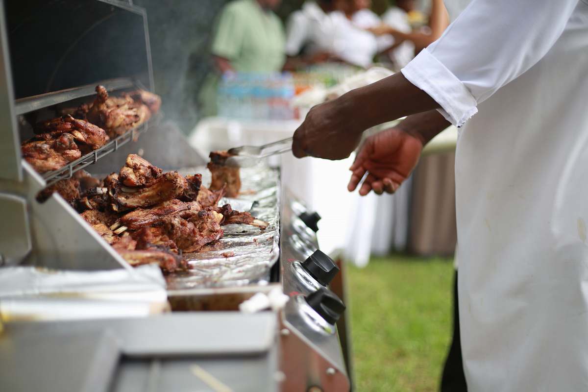 uganda person in white shirt grilling meat bbq