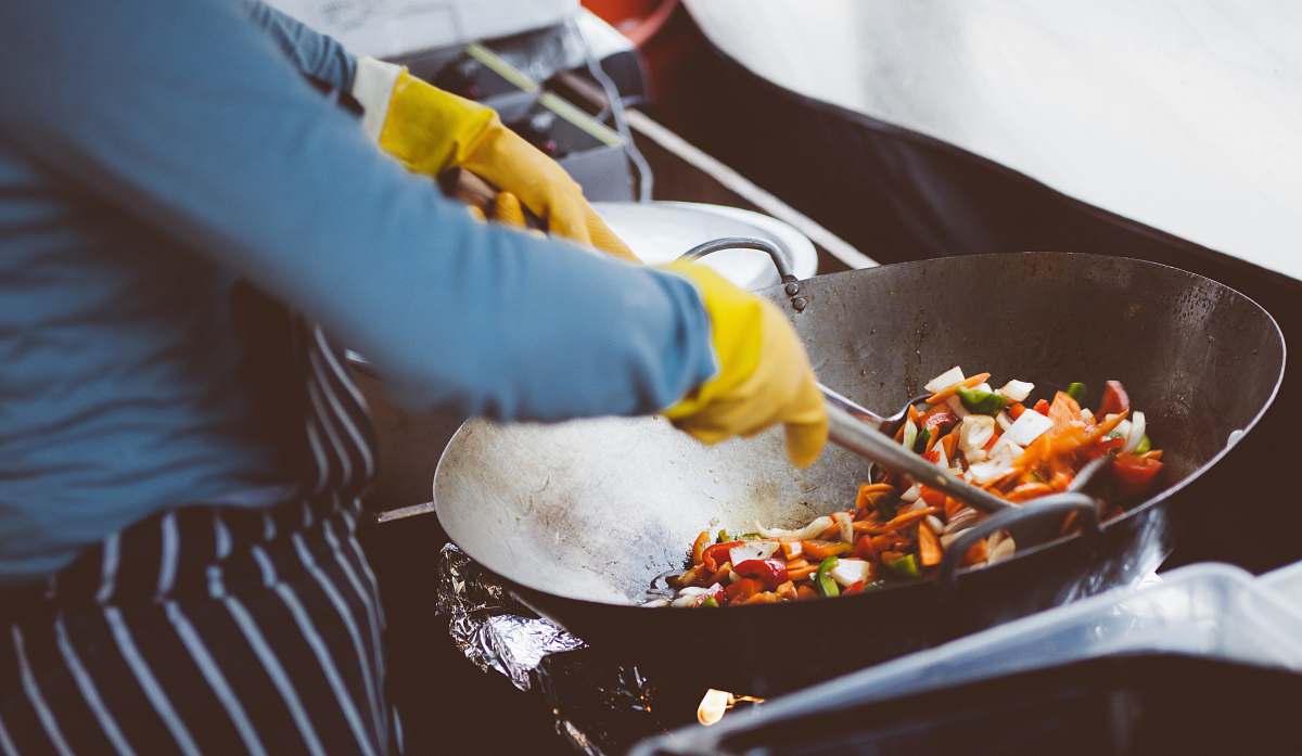 wok person mixing vegetable in wok person