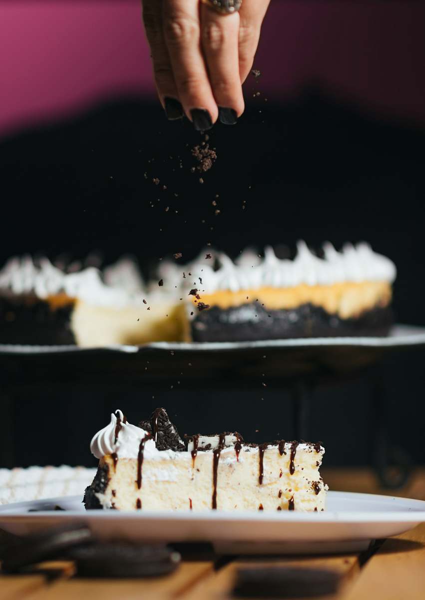 dessert person pouring chocolate powder on baked cake cake