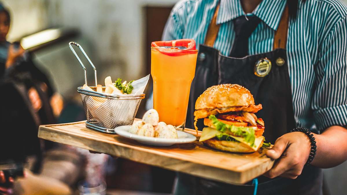 meal person serving burger with pitcher of juice burger