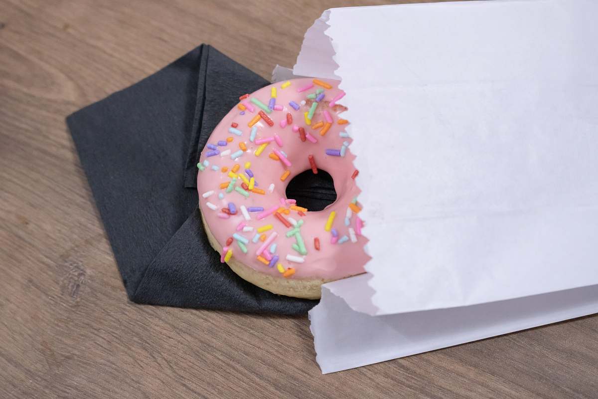 dessert pink donut on white paper bag pastry