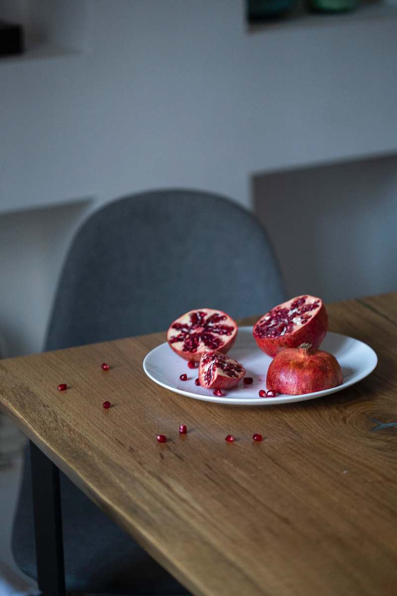 plant pomegranate fruit sliced into half on white plate produce