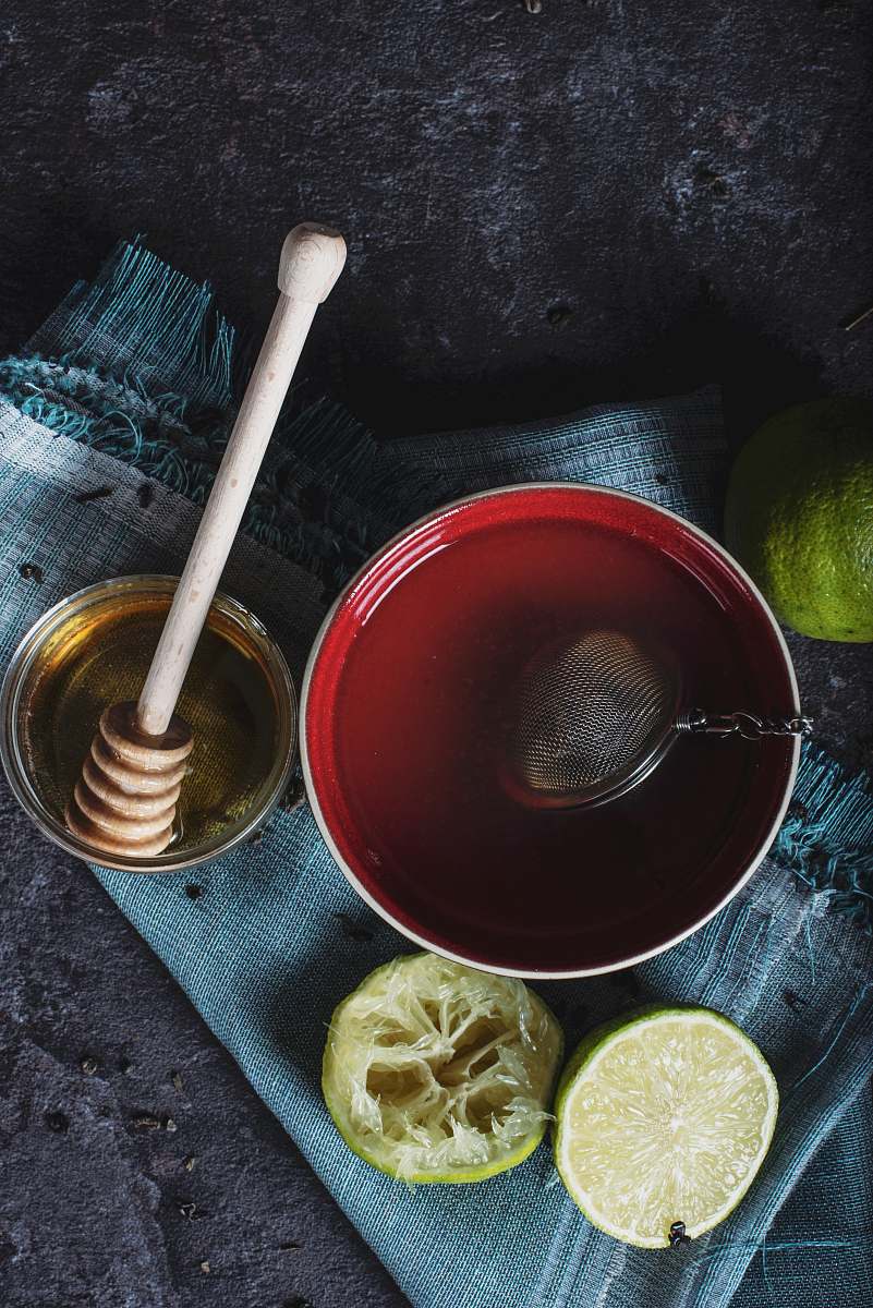 tea red ceramic bowl filled with water beside lime and honey drink