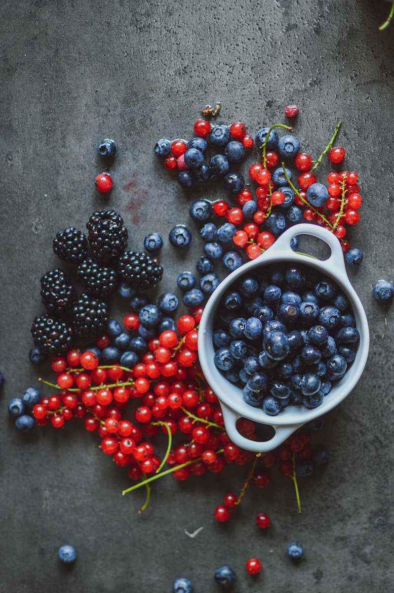 fruit round red and blue berries beside bowl blueberry