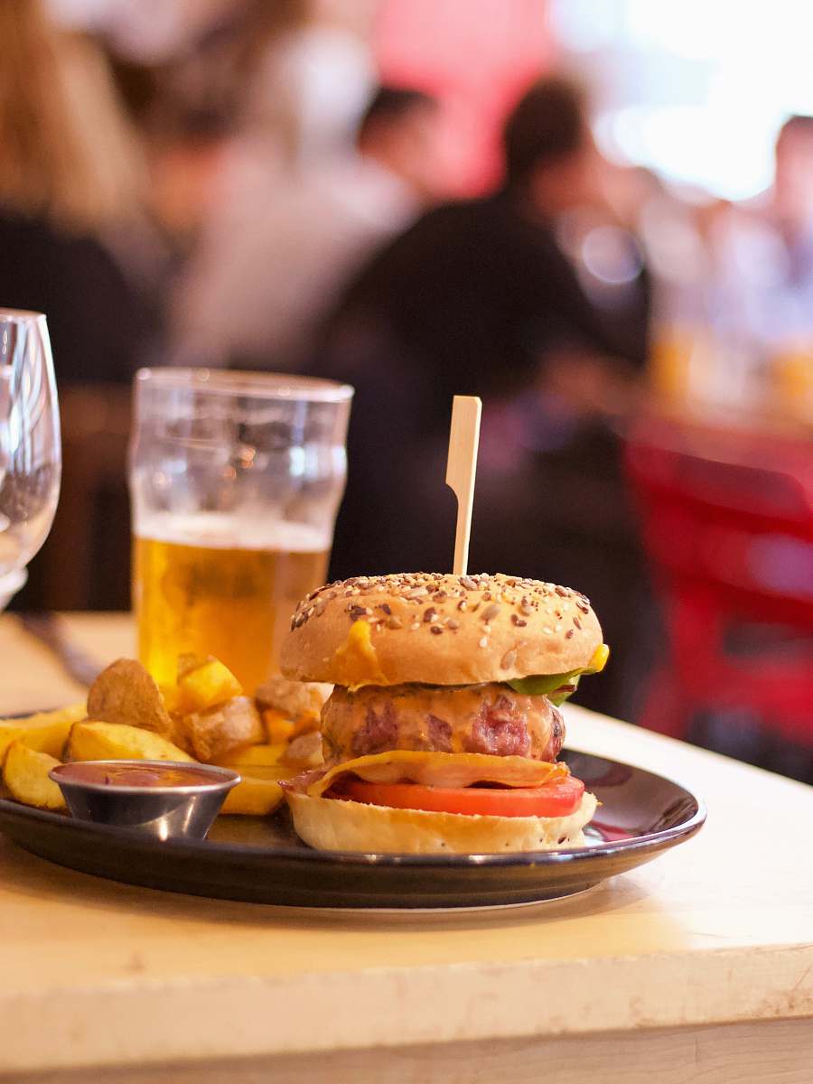 burger selective focus photography of hamburger and clear cup on black tray human