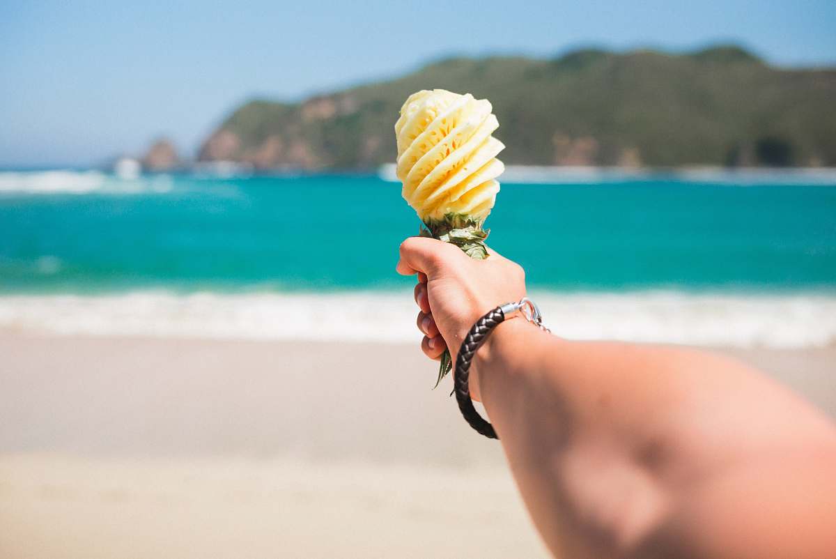 beach selective focus photography of person holding fruit near beach ocean