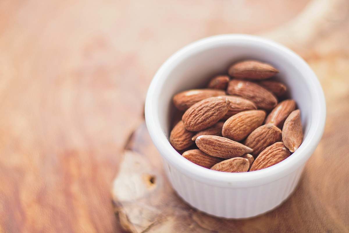 healthy shallow focus photography of almonds in white ceramic bowl almond
