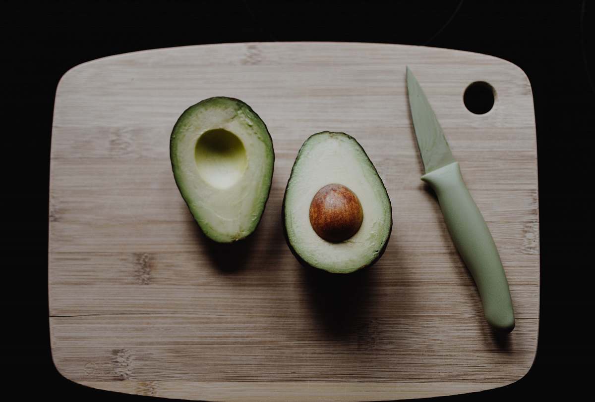 fruit sliced avocados on top of brown wooden chopping board in top view photography avocado