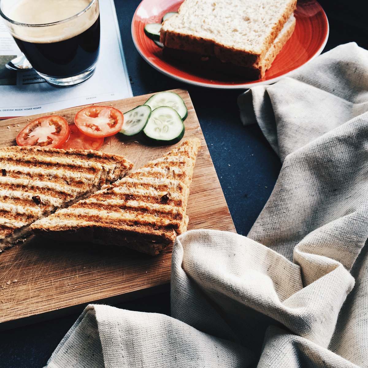 breakfast sliced grilled bread beside tomatoes and cucumbers on brown wooden board drink