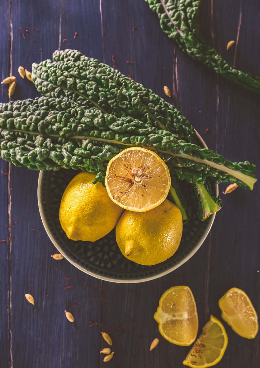 fruit sliced lemon and green leaves on gray stainless steel bowl lemon