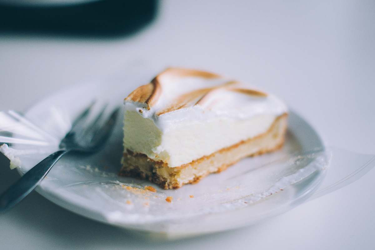 dessert sliced of cake on round white plate with silver fork cheesecake