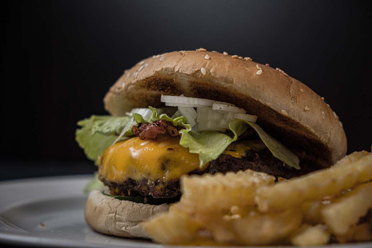 burger tasty burger with melted cheese and sesame seeds on top near potato fries yummy