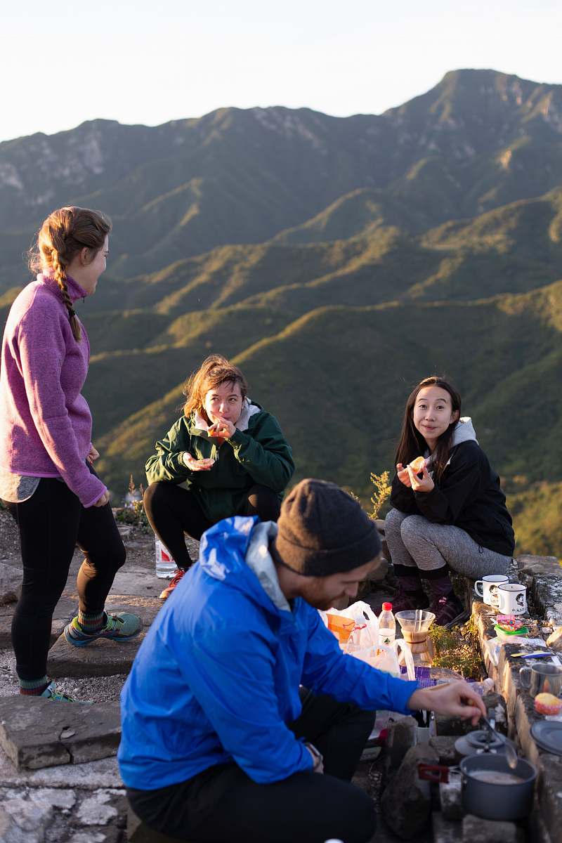 meal three woman and one man eating on top hill during daytime human