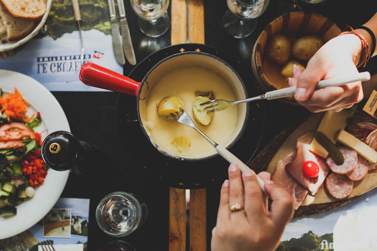 fondue two person holding fork dipping food on sauce switzerland