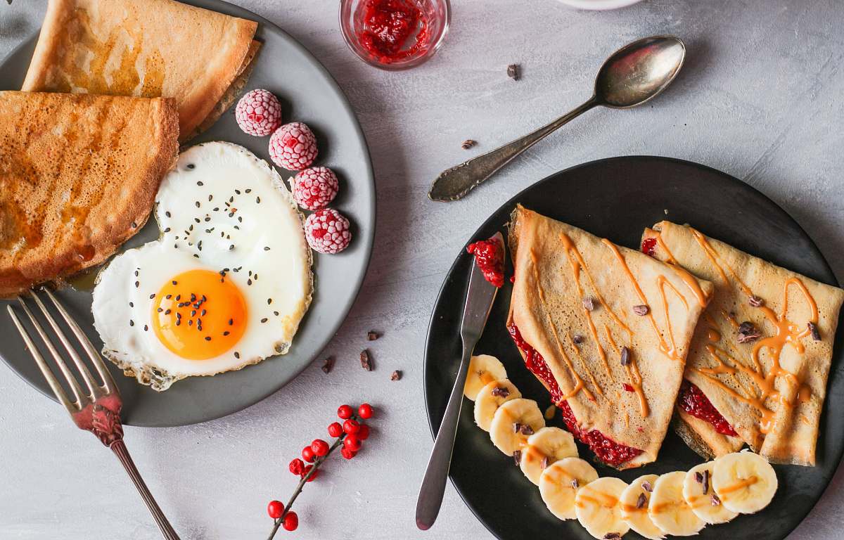 cutlery fried egg, bread and raspberry on plate spoon