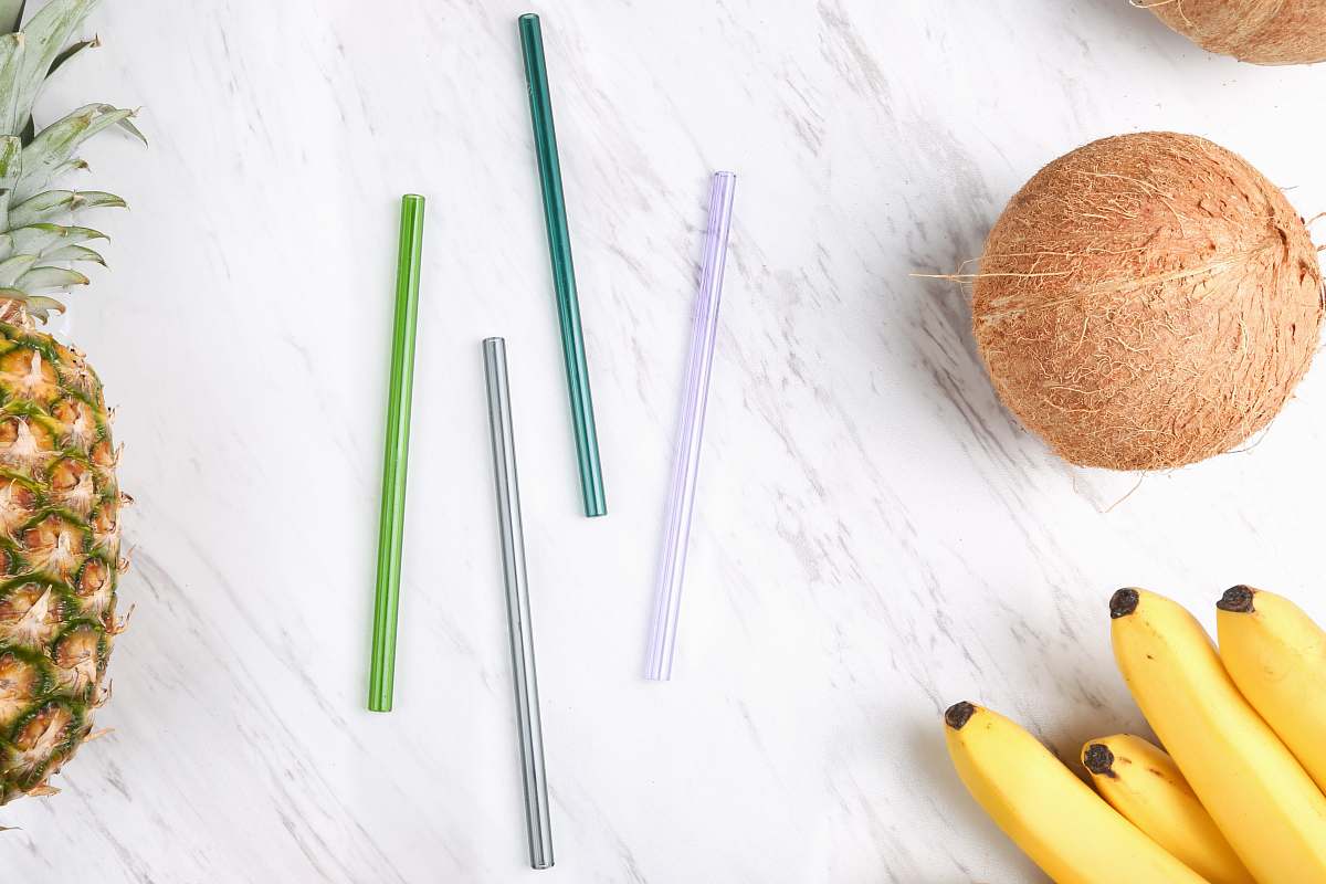food four assorted-color straws beside coconut, bananas, and pineapple pineapple