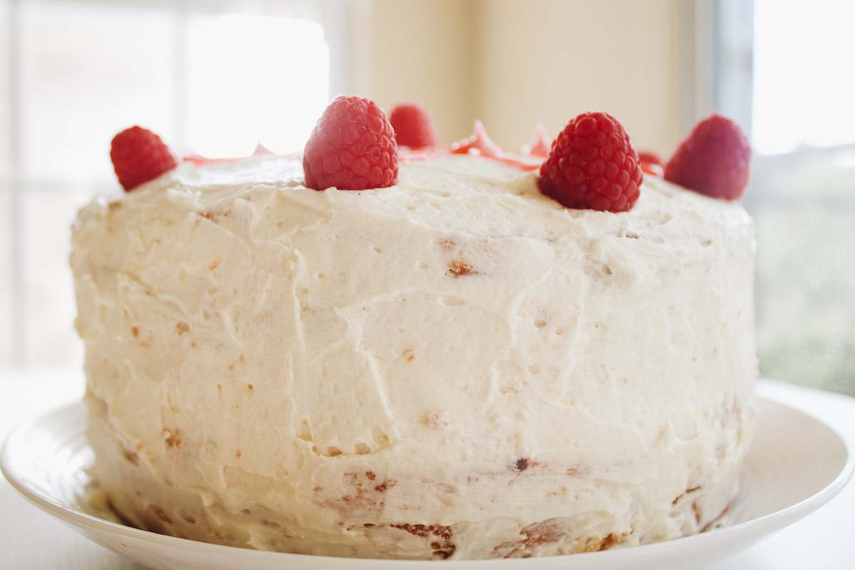 plant round white icing covered cake with raspberries raspberry