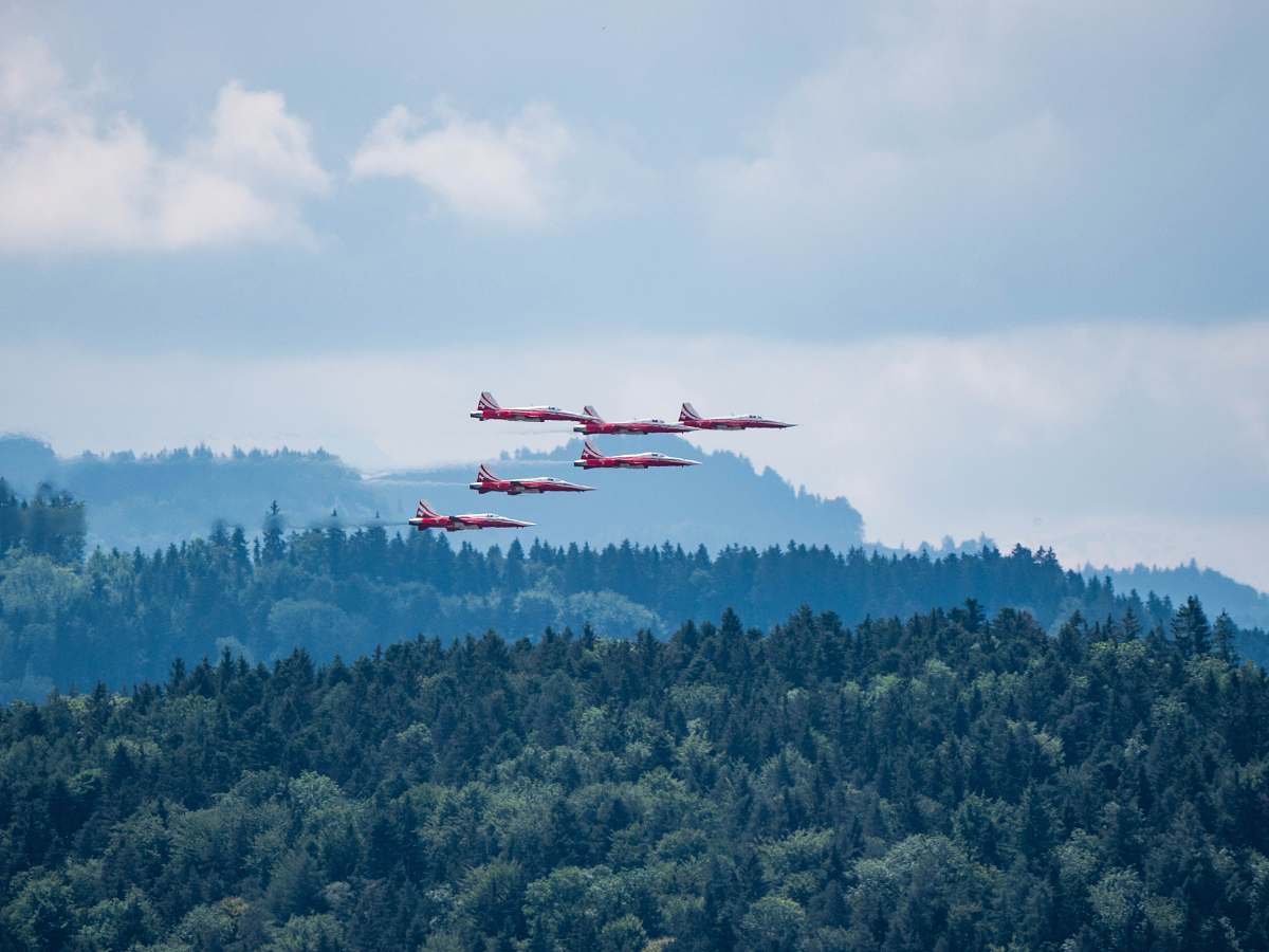 blue red-and-white airplanes flaying above green mountain wil