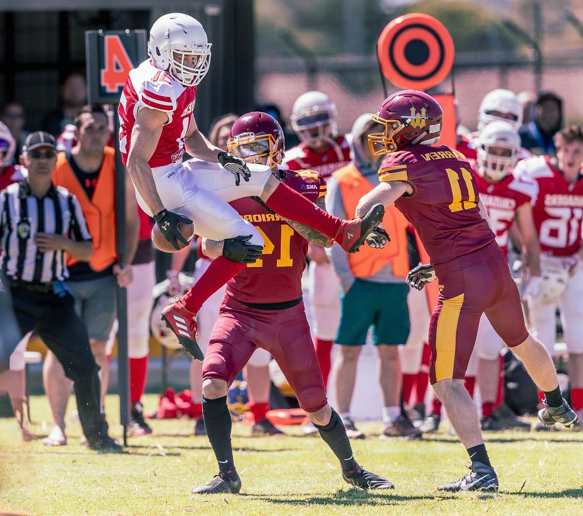 clothing American Football player about to land beside other player attempting to snatch the ball on field helmet