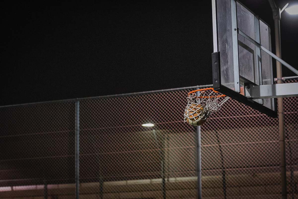 clothing basketball hoop near gray chain link fence during night sport