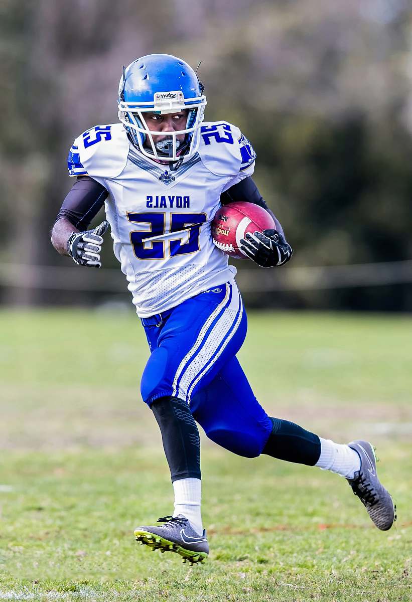 clothing football player running while carrying football helmet