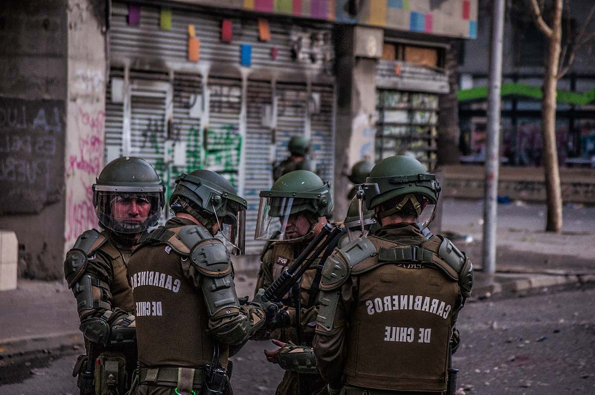 clothing group of Chilean police standing beside concrete structures helmet